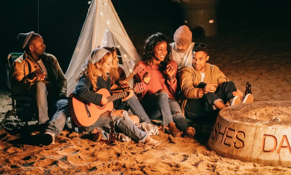 friends gathered around a campfire with a guitar