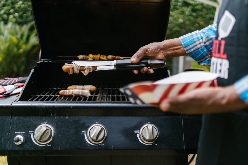 hands holding tongs by grill