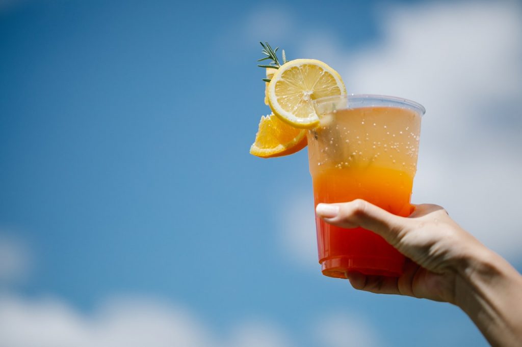 sunrise-style mocktail in plastic cup against blue sky