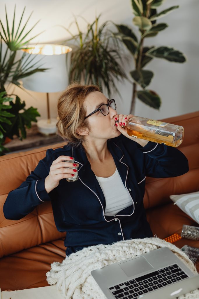 woman drinking from a tequila bottle while managing bills