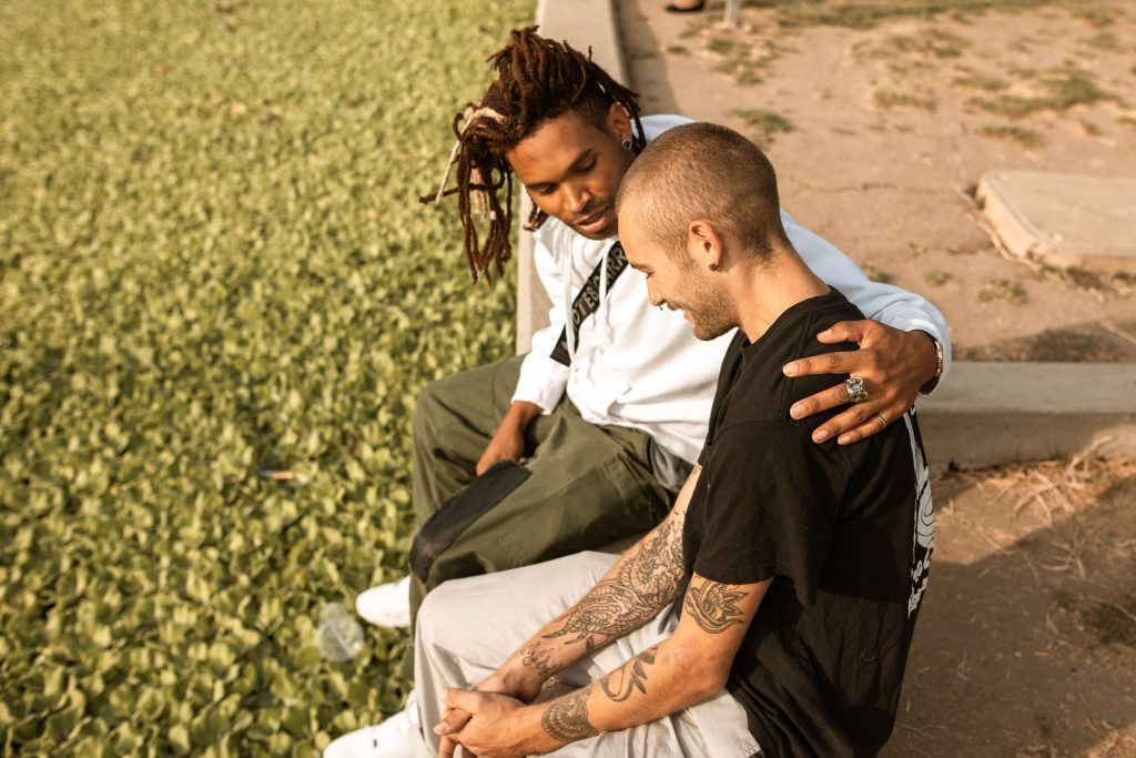 two young men sitting on curb talking out a problem