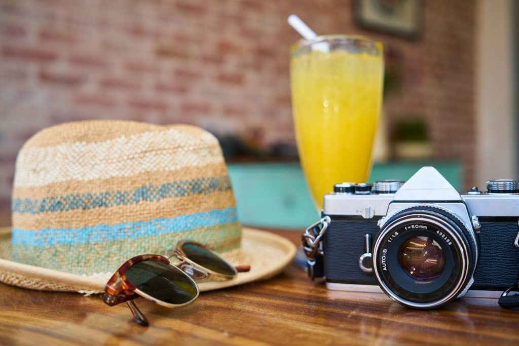 glass of orange juice, hat, and camera on table