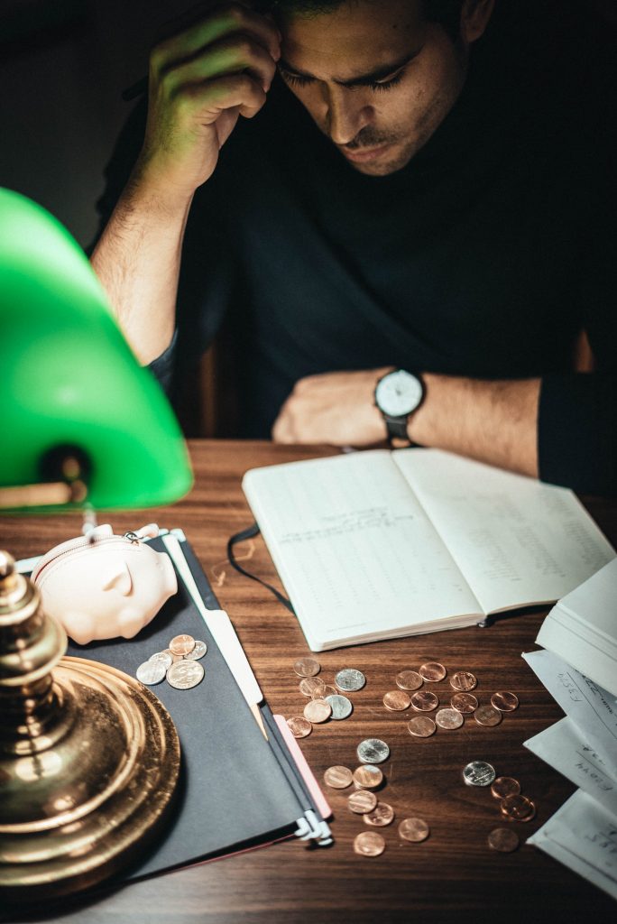 man scowling over financial books at desk with lamp