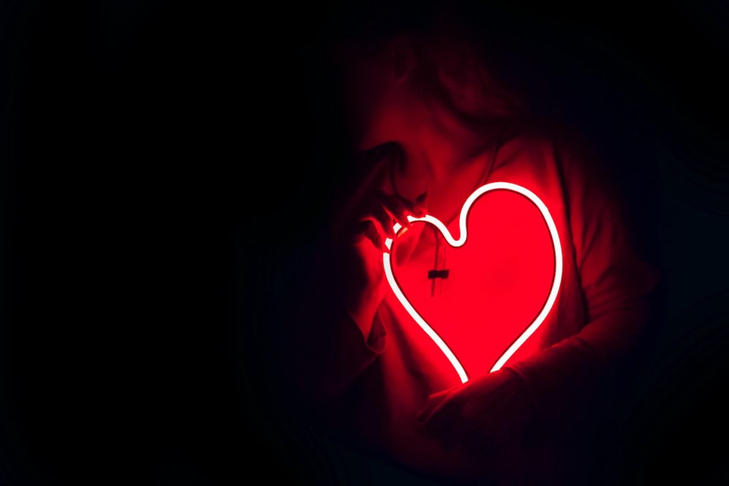 hand holding a red neon light in shape of heart