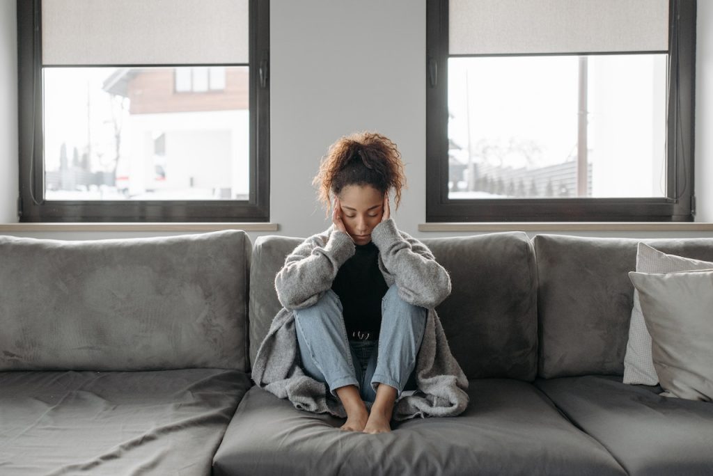 woman sitting on couch with head in her hands