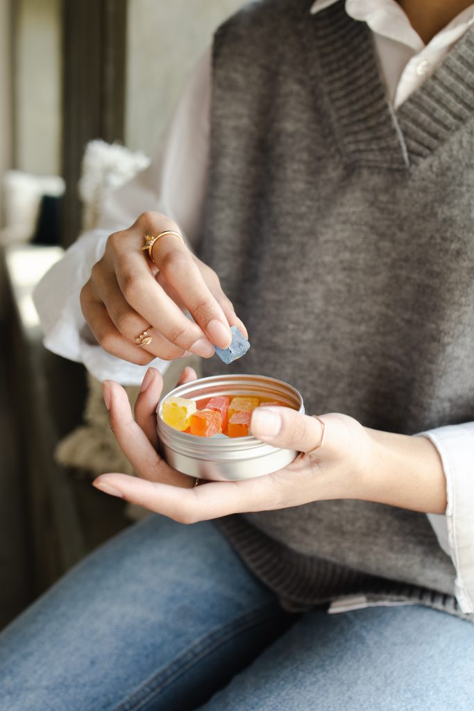 person eating CBD gummies from tin container