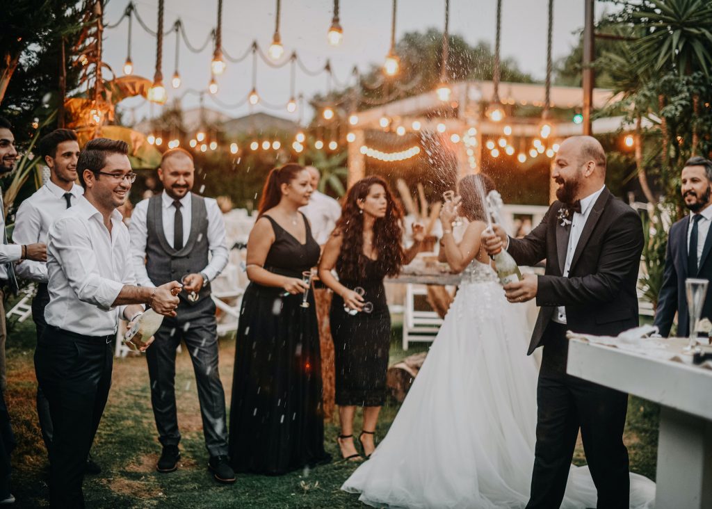 man popping champagne bottle at wedding reception