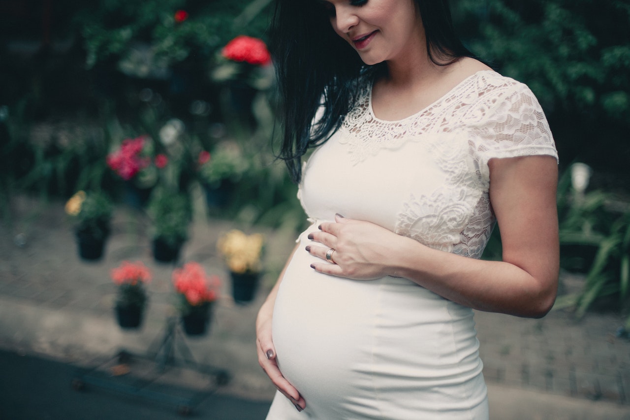 expectant mother in white holding her belly