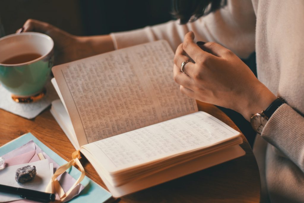 person reviewing journal with a cup of tea