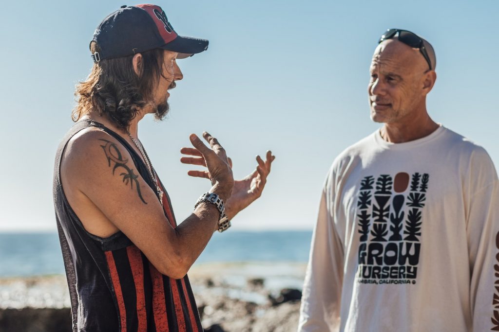 two men talking with sea in the background