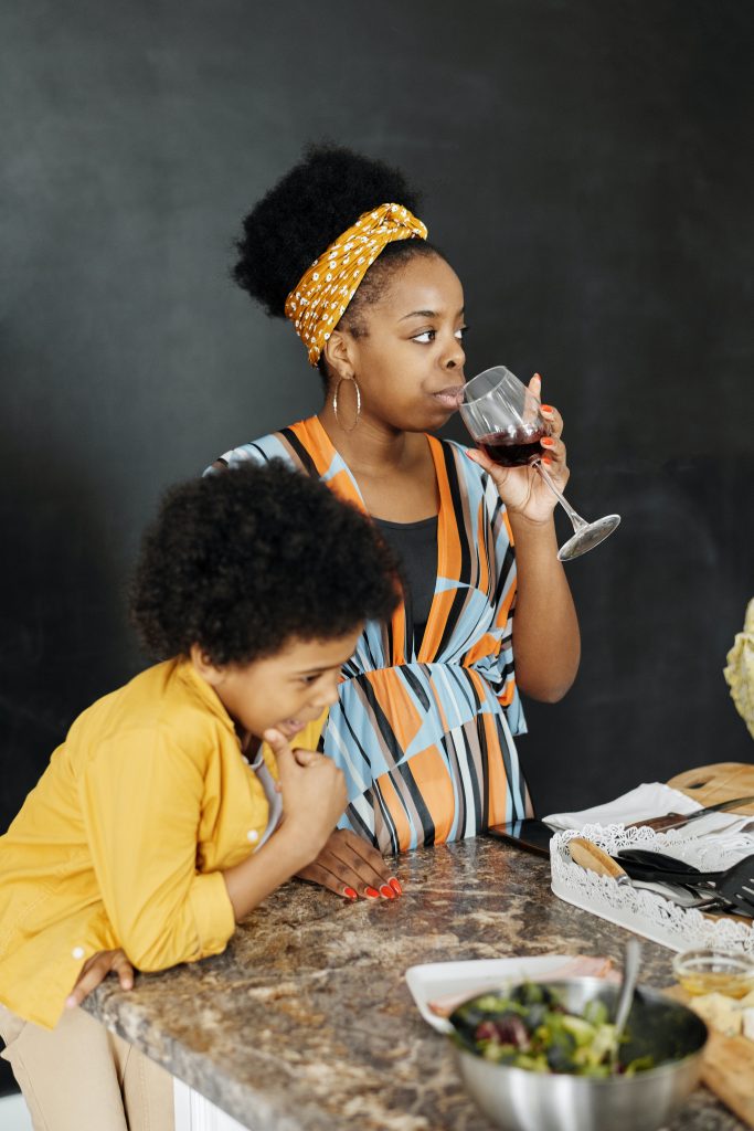 mother drinking wine and frowning next to her son