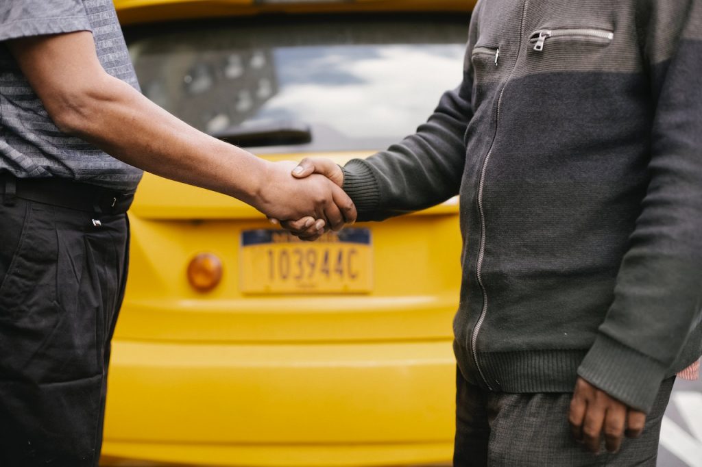 two men shaking hands on a city street