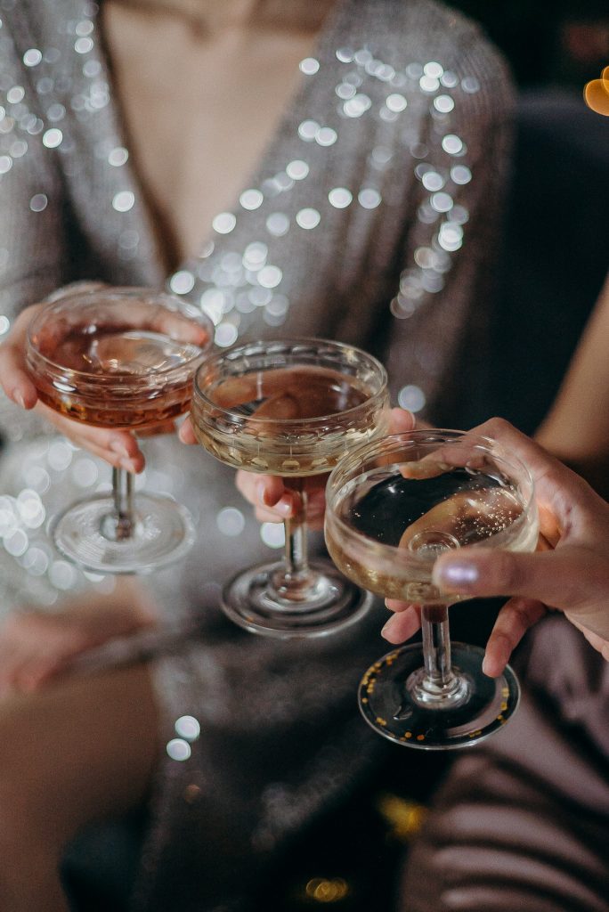 people in cocktail gowns raising glasses