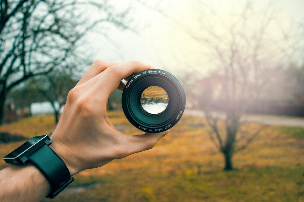 hand holding a focusing lens up to a fall landscape