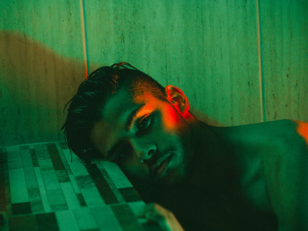 man leaning head on wall under green light