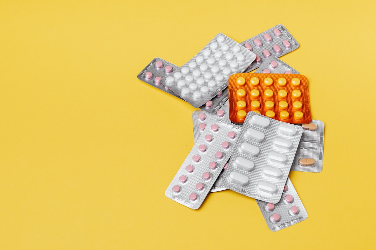 several medications in blister packs against a yellow background