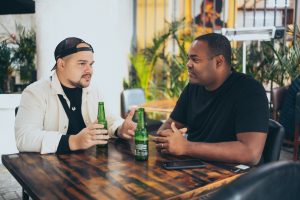 two men sitting and drinking beer while having a relaxed discussion