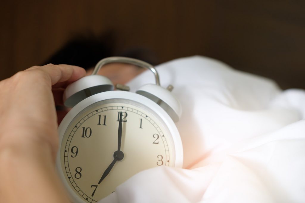 hand clutching alarm clock