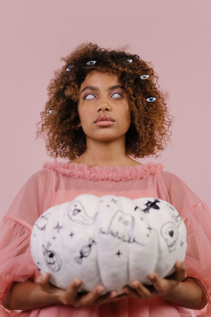 young woman with a scary expression holding white pumpkin