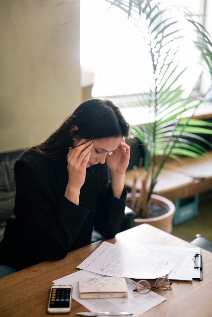 woman at a desk massaging her temples and feeling fatigued