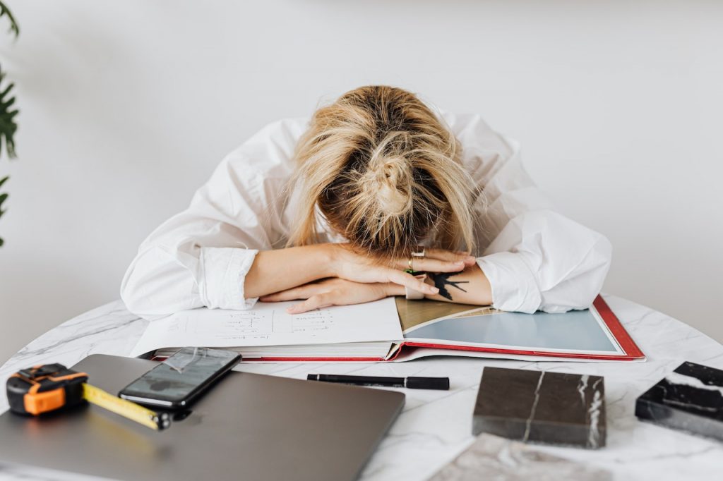 woman with her head down at a desk feeling overwhelmed