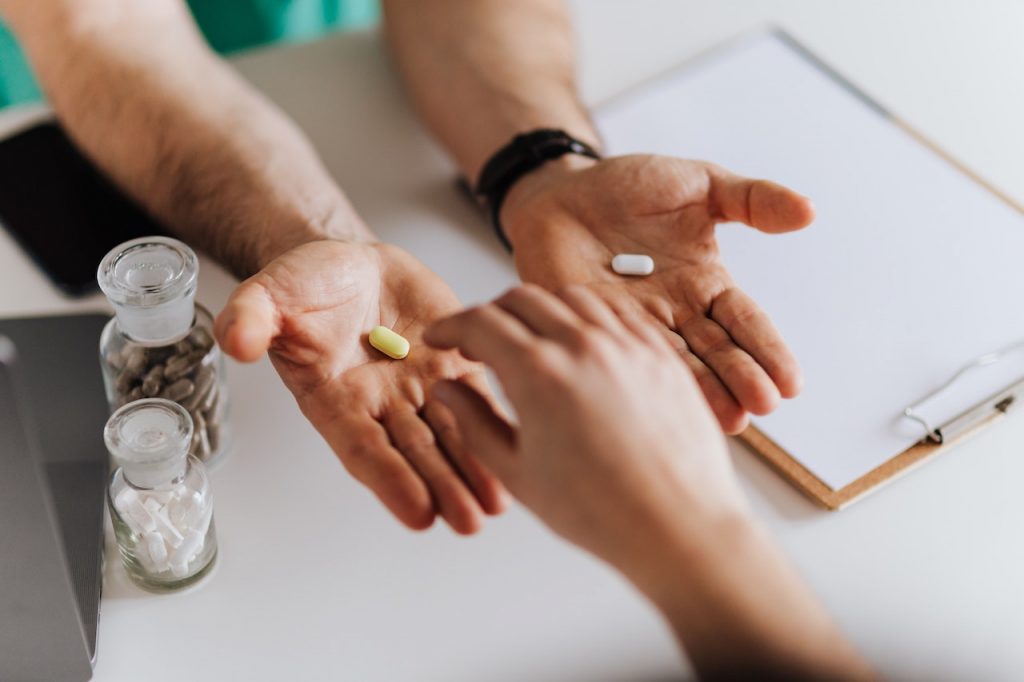 doctor holding out hands offering two different pills