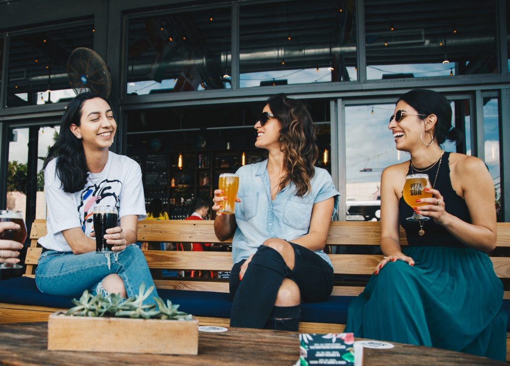 three women sitting and talking outside at a beer garden