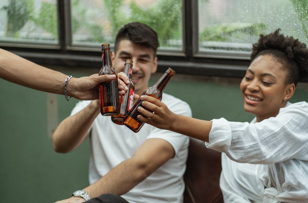 friends clinking beers at outdoor cafe