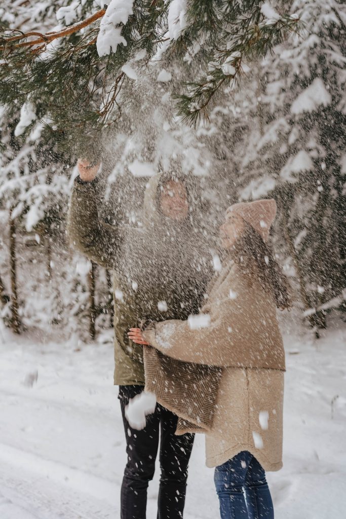couple playing in snow beneath trees