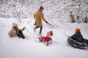 family playing in the snow with sleds