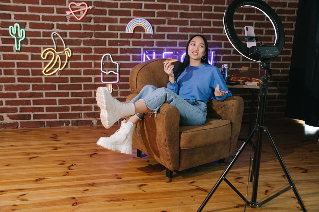 influencer recording video in front of brick wall with neon signs