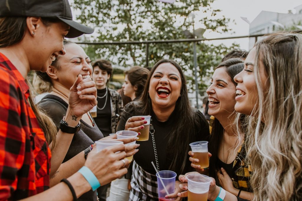 group of female friends drinking beer together and laughing