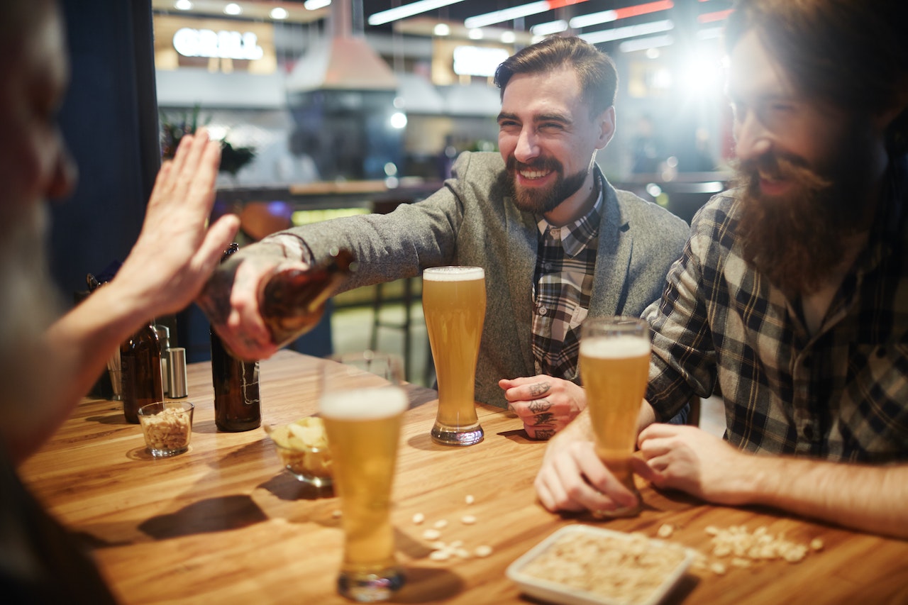 group of male friends drinking beer at a bar