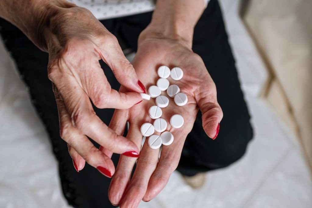 woman's hands holding a dozen white circular pills