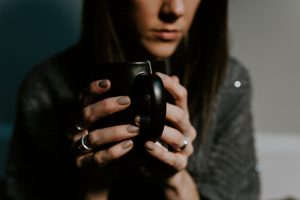dark shot of woman drinking tea and feeling unwell