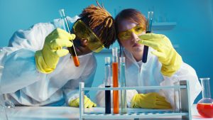 man and woman in lab coats looking at test tubes with bright blue background