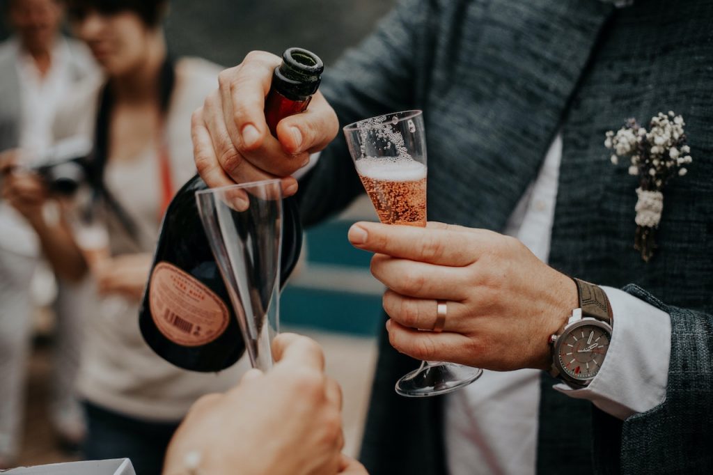 man in suit pouring champagne into glass at celebration