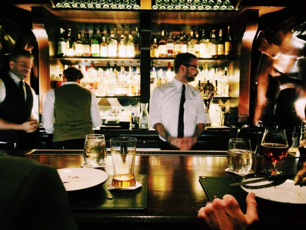 bartenders standing behind a busy bar