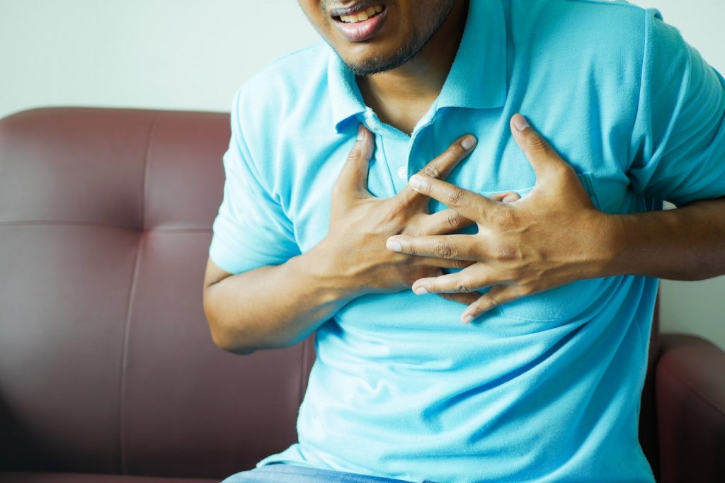 man in blue shirt clutching chest and grimacing