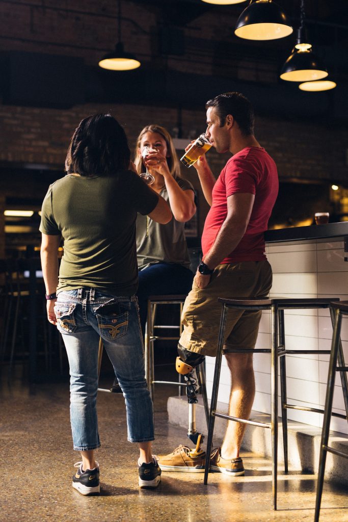 three friends drinking at a bar together during the day