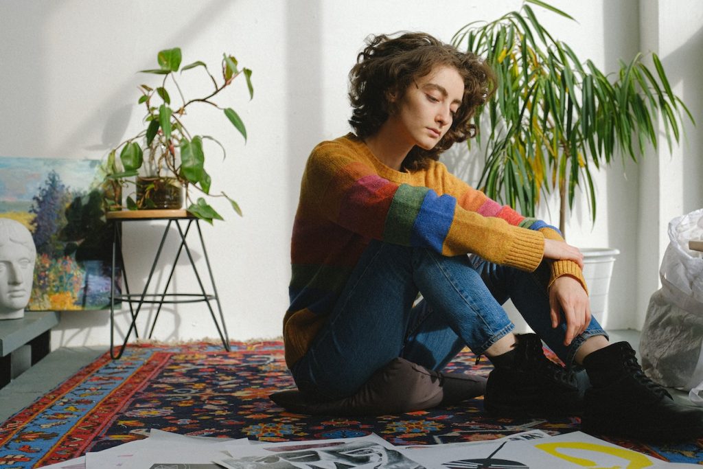 sad-looking person in colored shirt sitting on floor