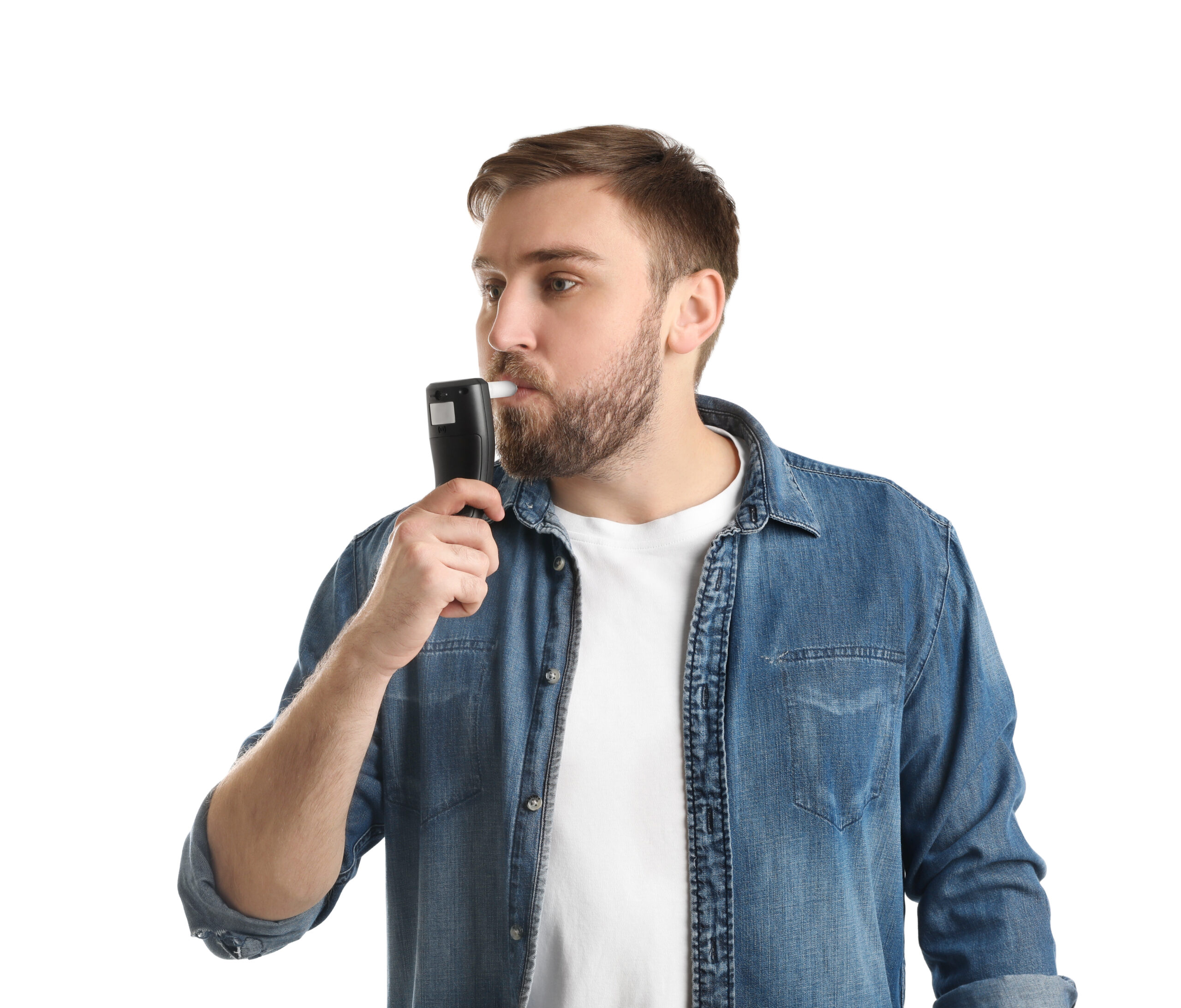 Man holds a breathalyzer in his mouth and blows into it.