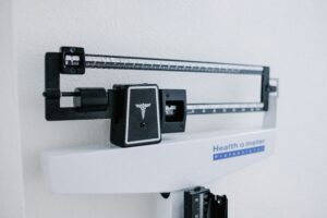 The scale at a doctors office is shown against a plain white wall.